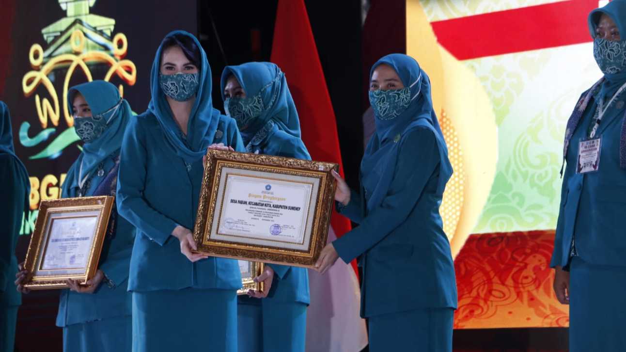 Ketua TP-PKK Sumenep, Nia Kurnia Fauzi saat menerima piagam penghargaan dari Ketua TP-PKK Jatim Arumi Bachsin di puncak peringatan HKG PKK ke- 48 (Dok. Prokopim Pemkab Sumenep).