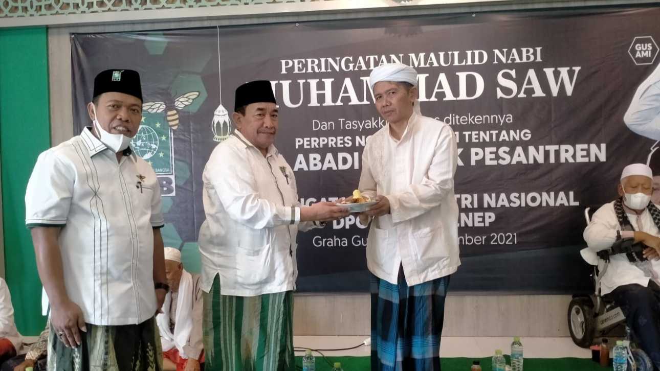Ketua DPC PKB Sumenep, KH. Imam Hasyim memberikan potongan tumpeng kepada Ketua Dewan Syuro, KH. Nasikh Fauzi.