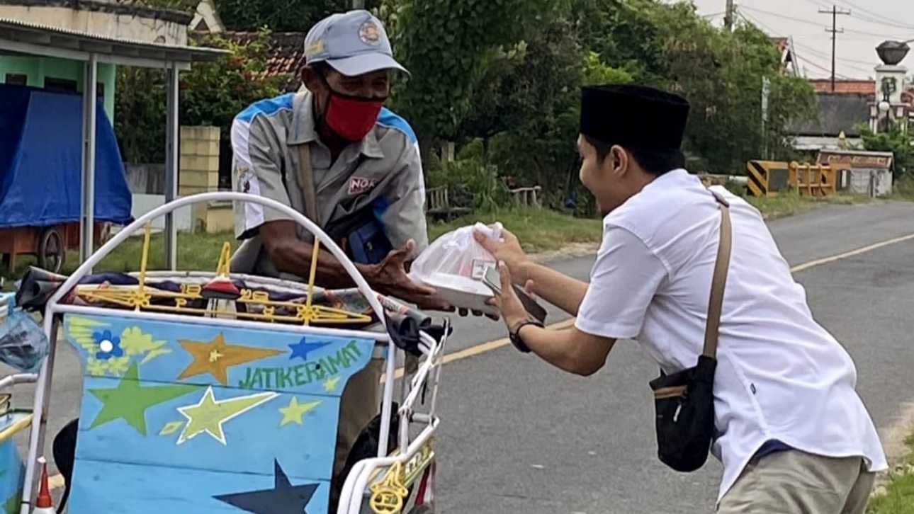 Salah seorang pemuda Taretan Ngopi Sumenep membagikan takjil kepada tukang becak.